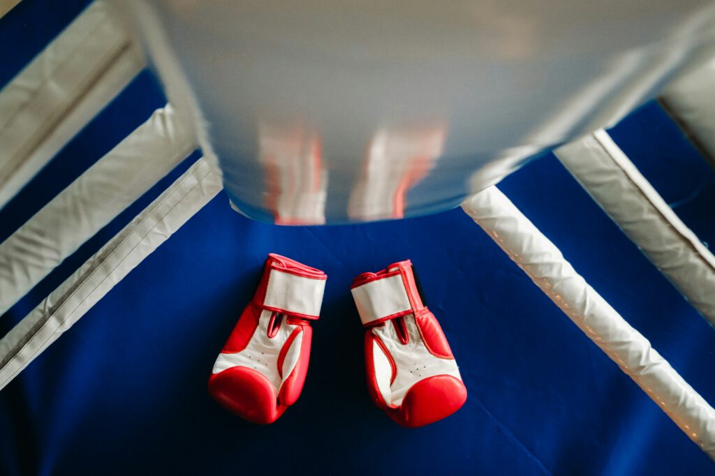 Close-up of red boxing gloves on the floor of a blue boxing ring